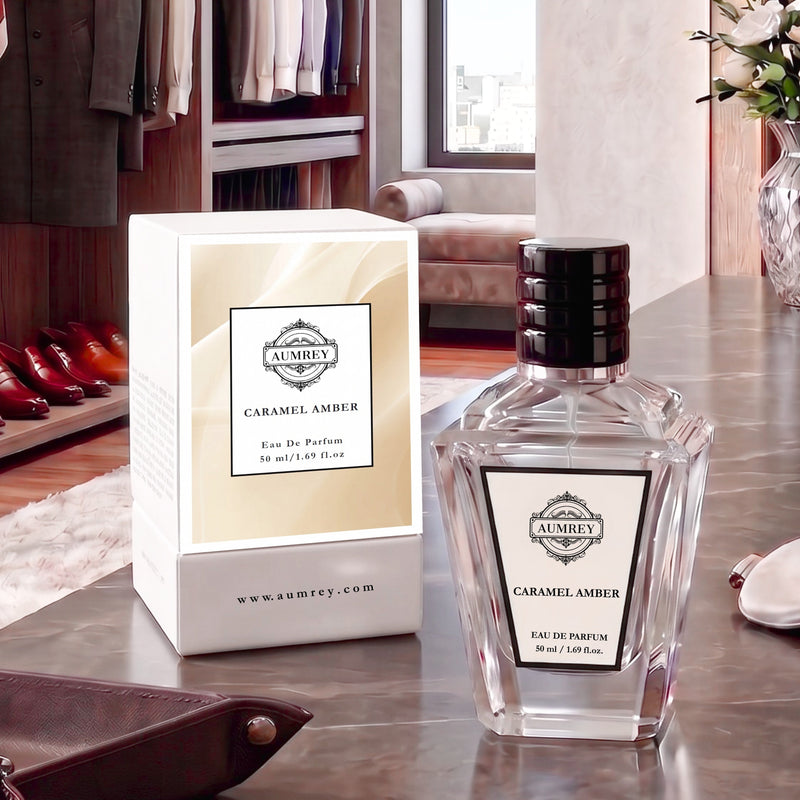 A bottle of Aumey Caramel Ambre Eau De Parfum next to its white and beige packaging box, displayed on a dark wooden table in a luxury dressing room setting.