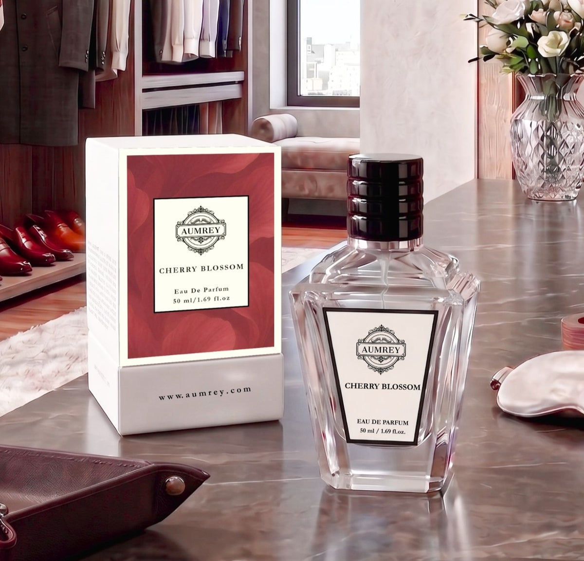 A bottle of Audie's Cherry Blossom Eau De Parfum next to its white and red packaging box, displayed on a polished marble countertop in a luxurious room setting.