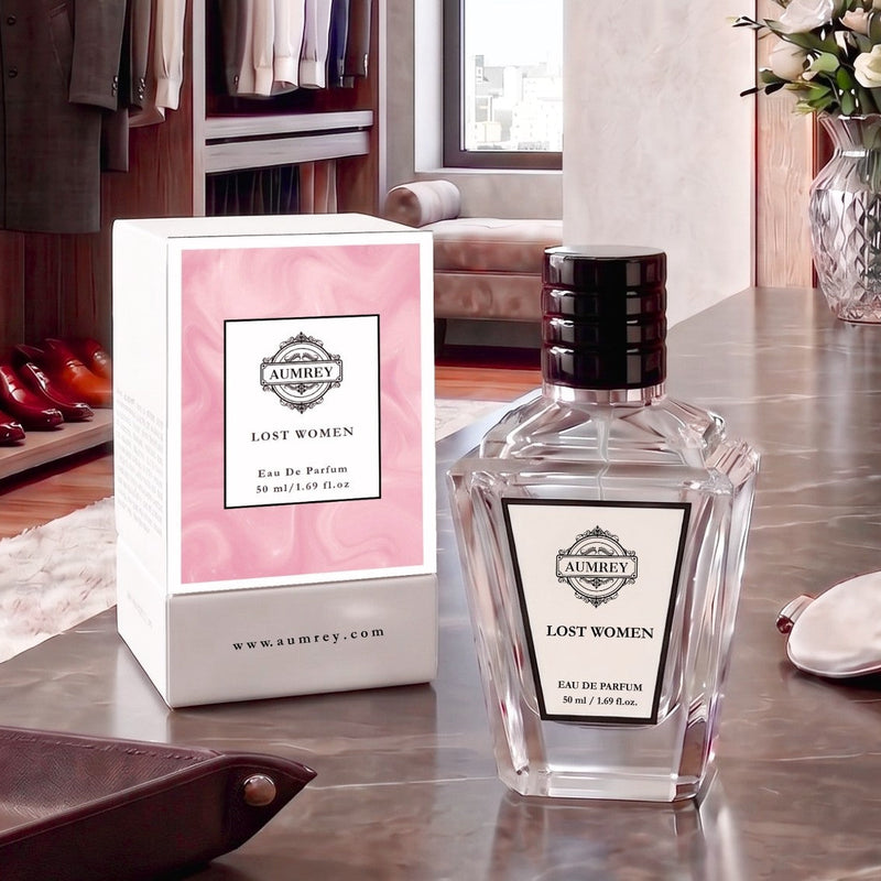 A bottle of Aumrei 'Lost Women' Eau De Parfum next to its pink and white box, displayed on a polished marble countertop in a stylish, modern room setting.