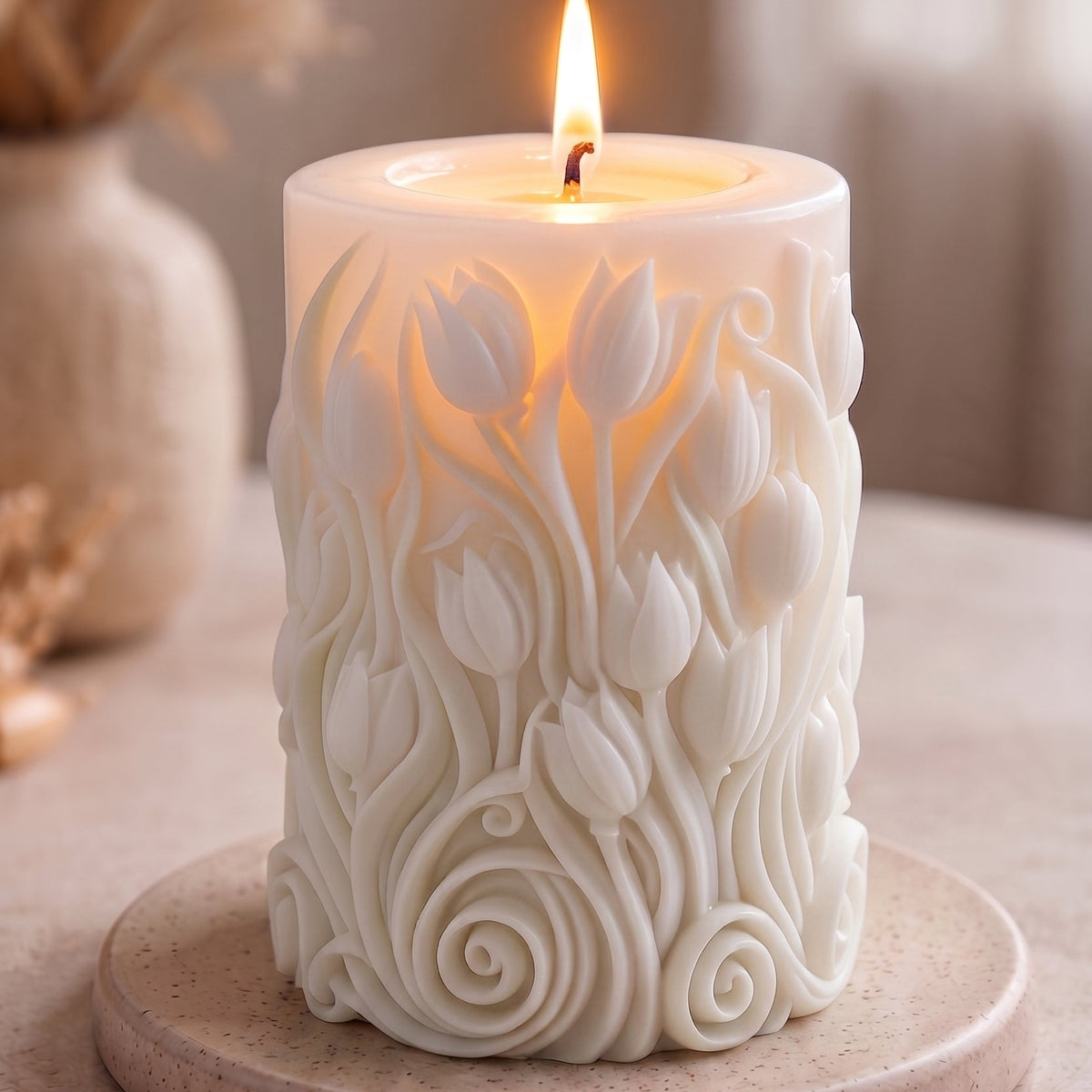Decorative candle with floral patterns on a stone base, lit with a warm glow.